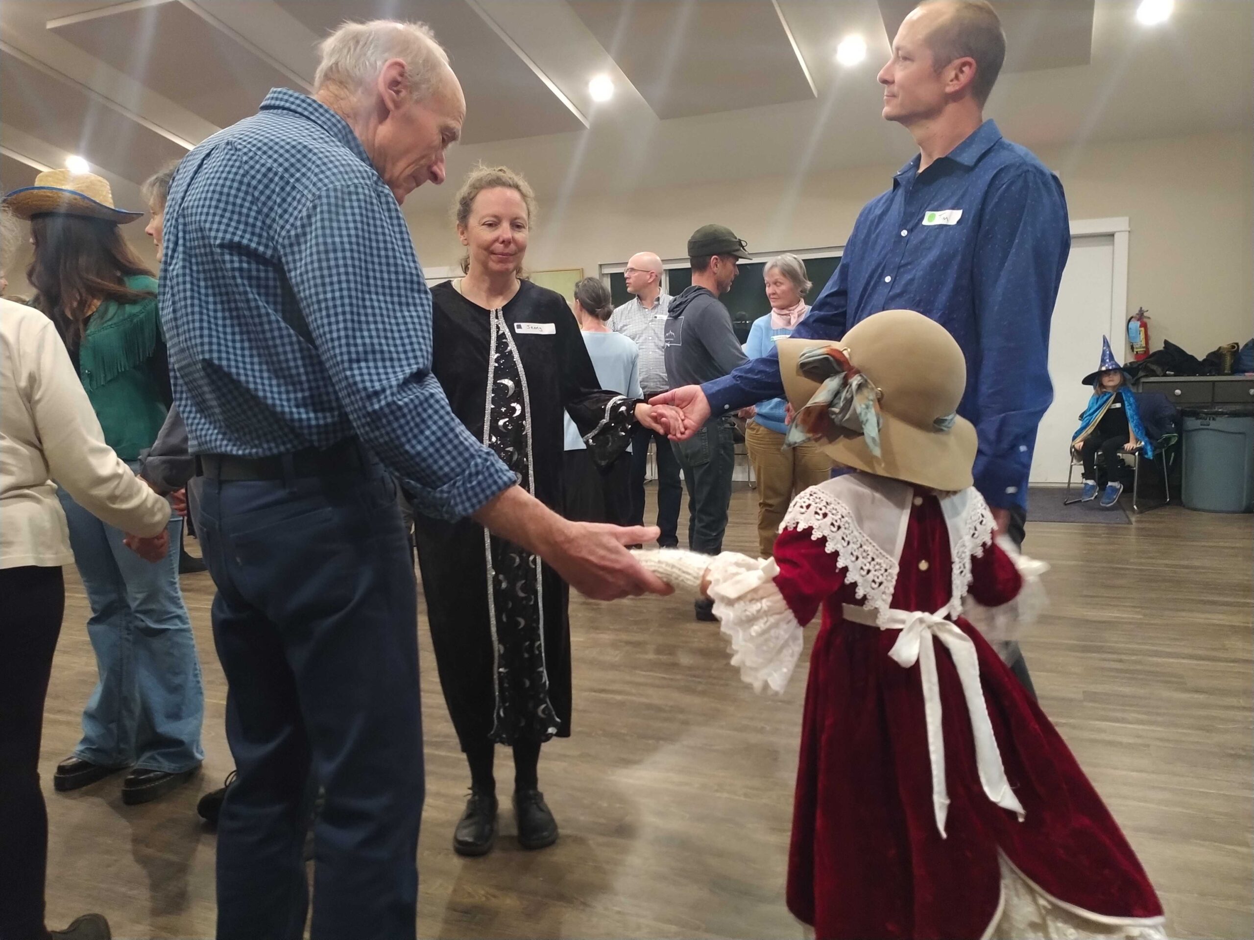 Group of contra dancers listening to caller's instructions for the next dance. Group consists of dancers from a young girl to a man in his 80's.